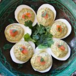 several Spicy Deviled Eggs in a circular pattern in a green bowl