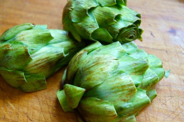 raw artichoke halves, round side up on cutting board