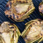 a few grilled artichoke halves on a grill