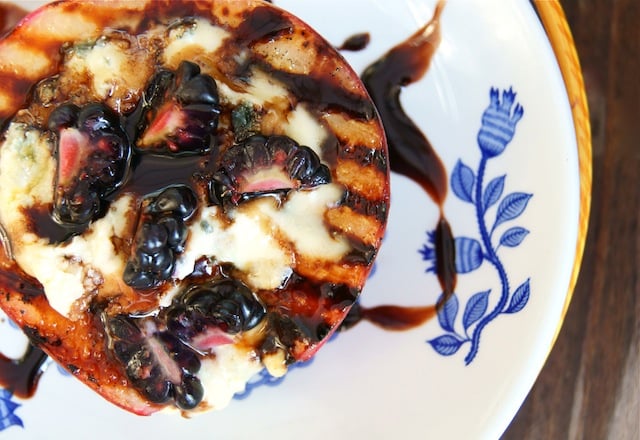 Top view, close-up of blue cheese stuffed grilled peach with blackberries