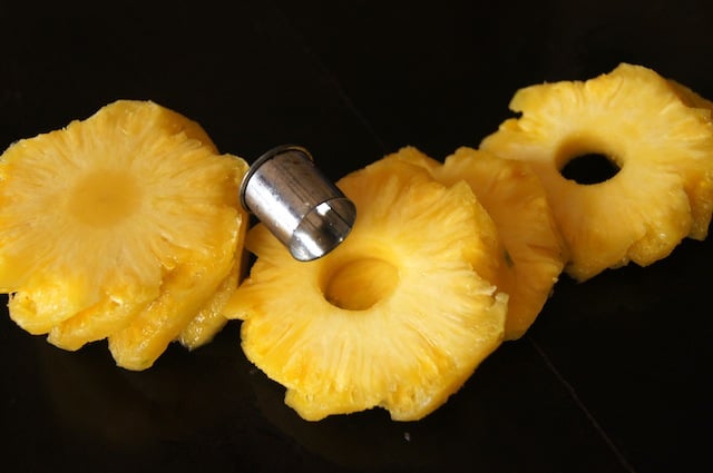 peeled pineapple slices with core being cut out with round cutter