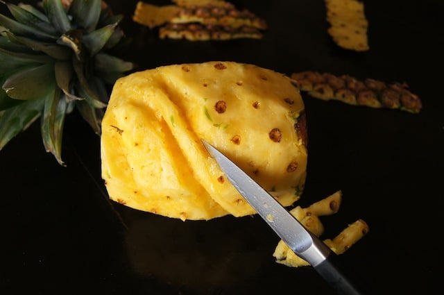 peeled pineapple on its side being cut