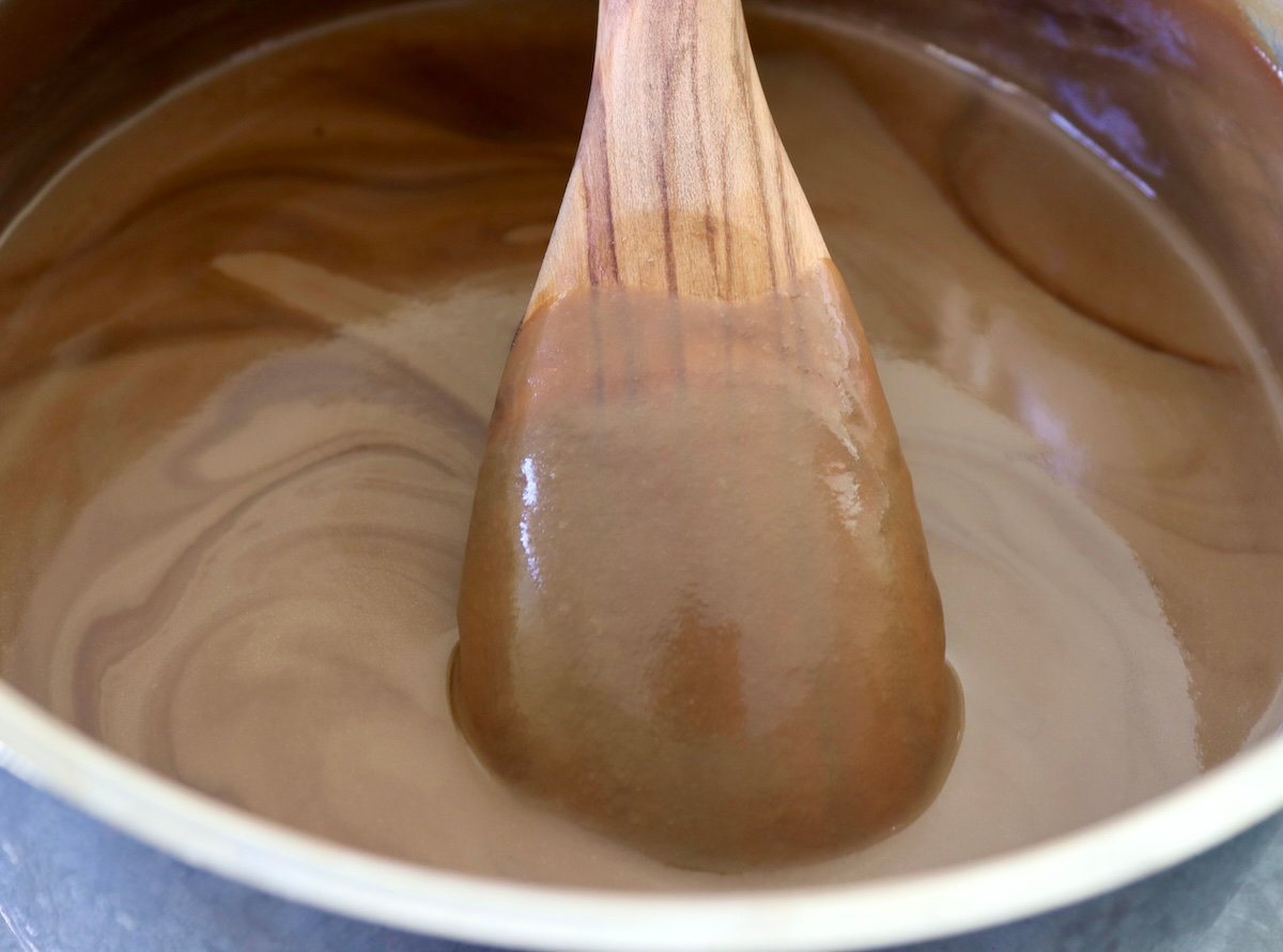 Thick espresso custard in a pot with a wooden spoon that's coated with it.