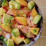 Avocado Salmon Bowl with Peaches in ceramic bowl on sushi mat