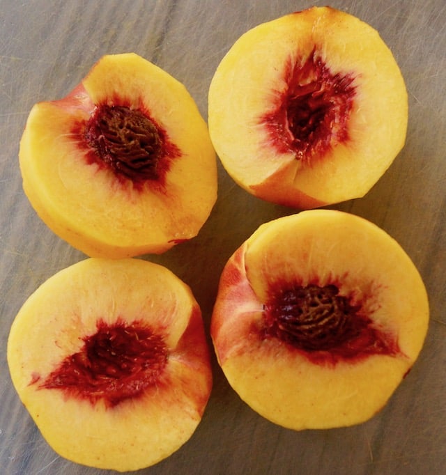 Halved peaches on cutting board.