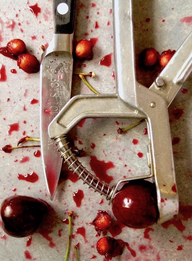 a few cherries, pits and stems with juice and cherry pitter