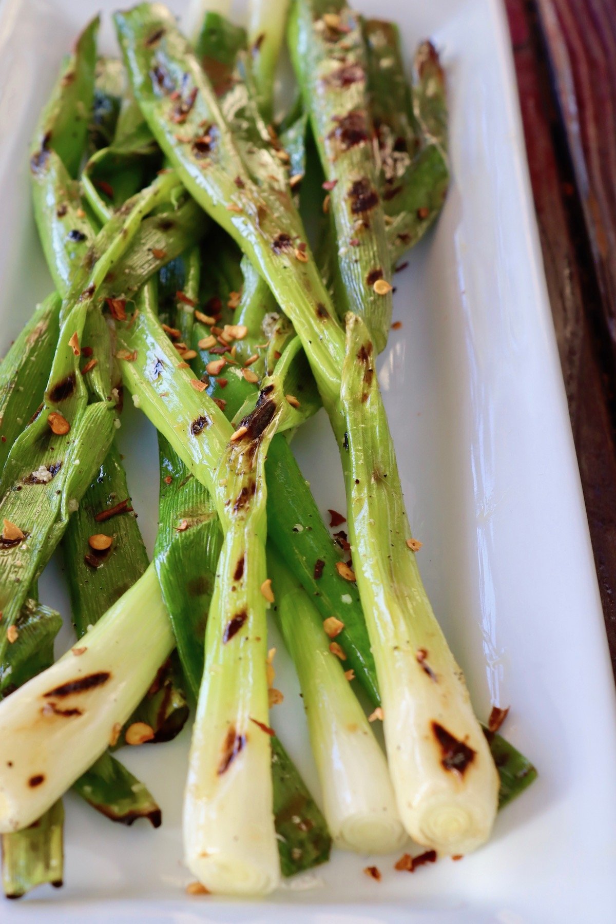Several grilled scallions on a white plate