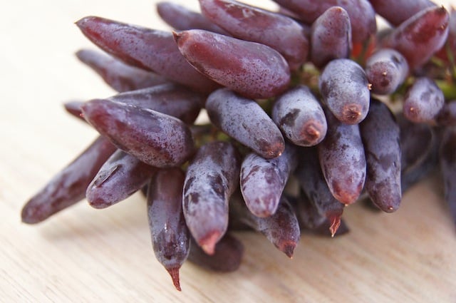 1 bunch of Witch Fingers Grapes on a light surface.