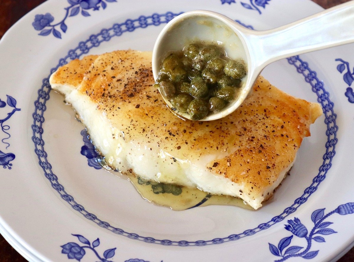Lemon-Caper Sauce being spooned over Seared Chilean Sea Bass.