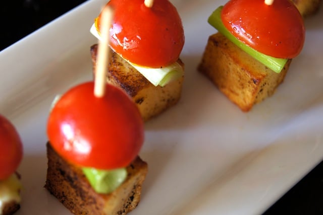 A few Smoky Potato-Pickled Tomato Bites on a white plate with toothpicks.