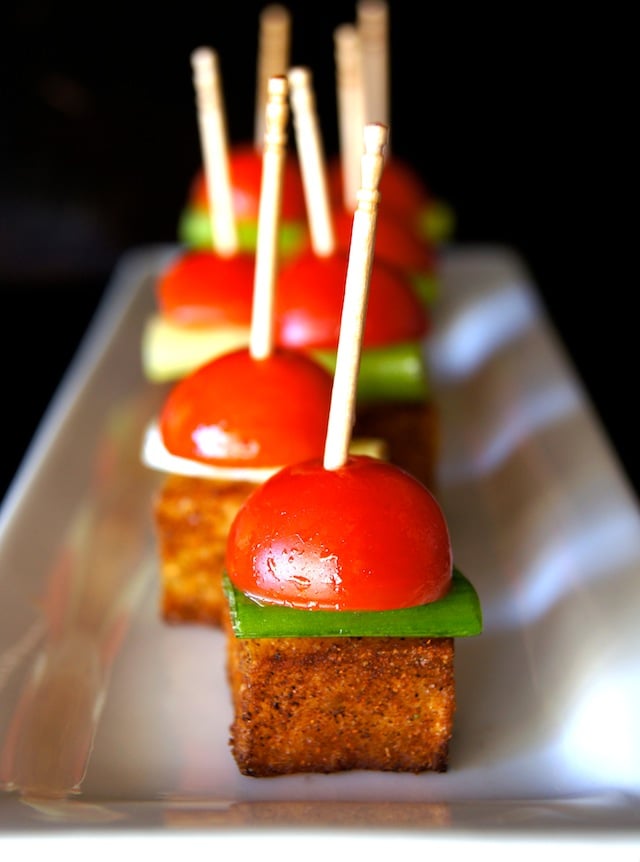 Smoky Potato-Pickled Tomato Bites lined up with toothpicks on a long white plate