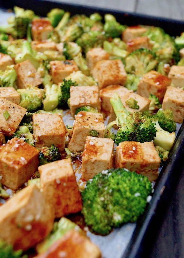 Tofu cubes and broccoli on a sheet pan dirzzled with Sesame Sriracha Honey marinade