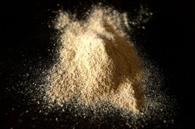 Small pile of mesquite flour on a dark table.