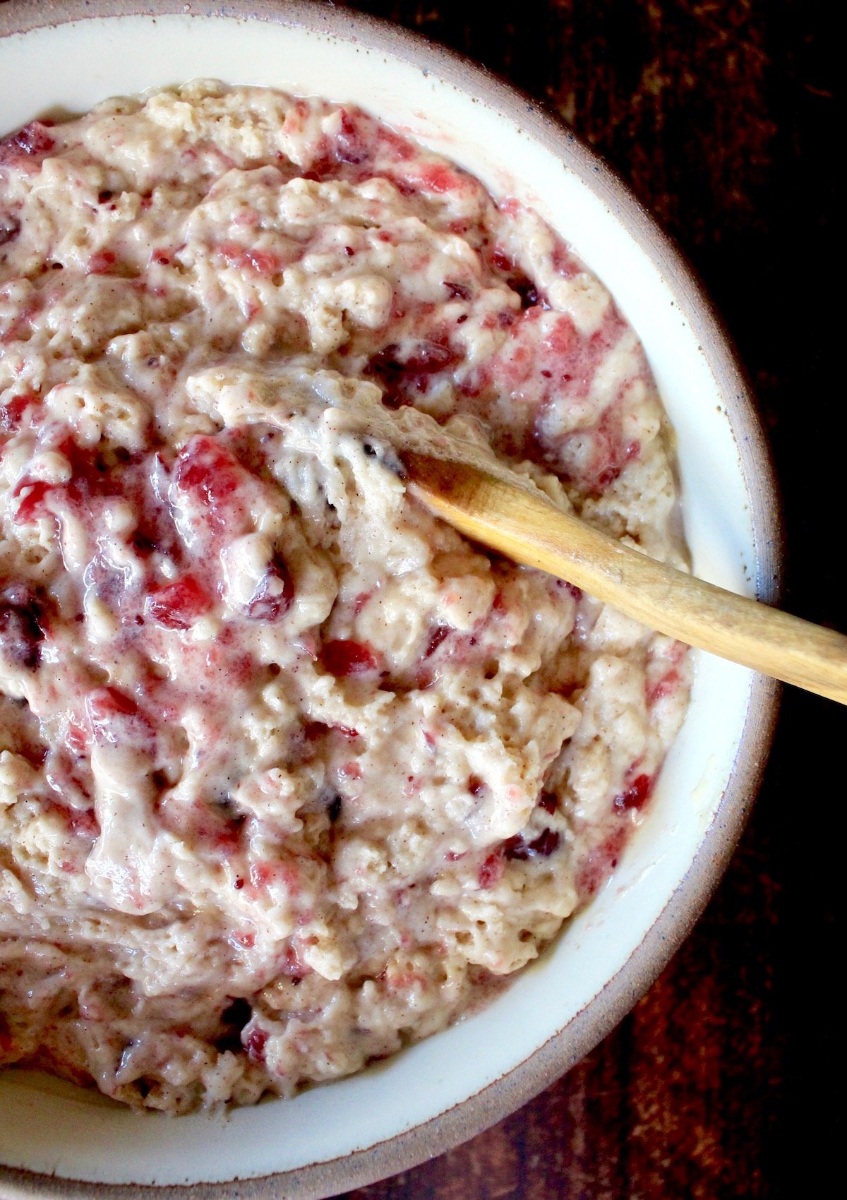 bowl with cranberry muffin batter with wooden spoon