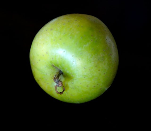 One Green Dragon Apple on a black background.