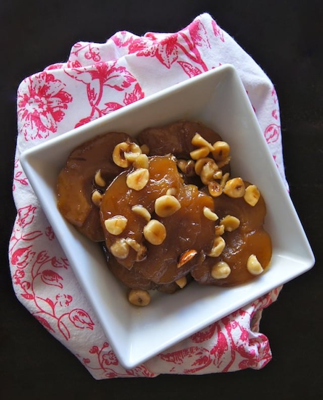 Hazelnut Honey Roasted Apples with chopped hazelnuts on top in a square white dish.