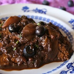 blueberry braised brisket sliced on a white and blue flowered plate