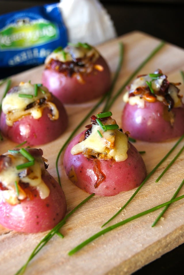 Several Cheddar Potato Bites with Cranberry Pecan Onions on a cutting board.