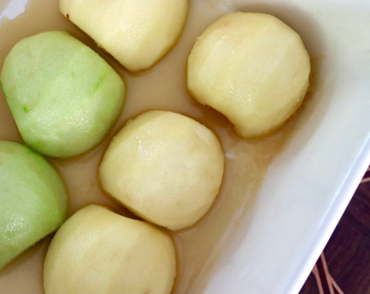 Peeled apple halves, round sides up, in a baking dish.