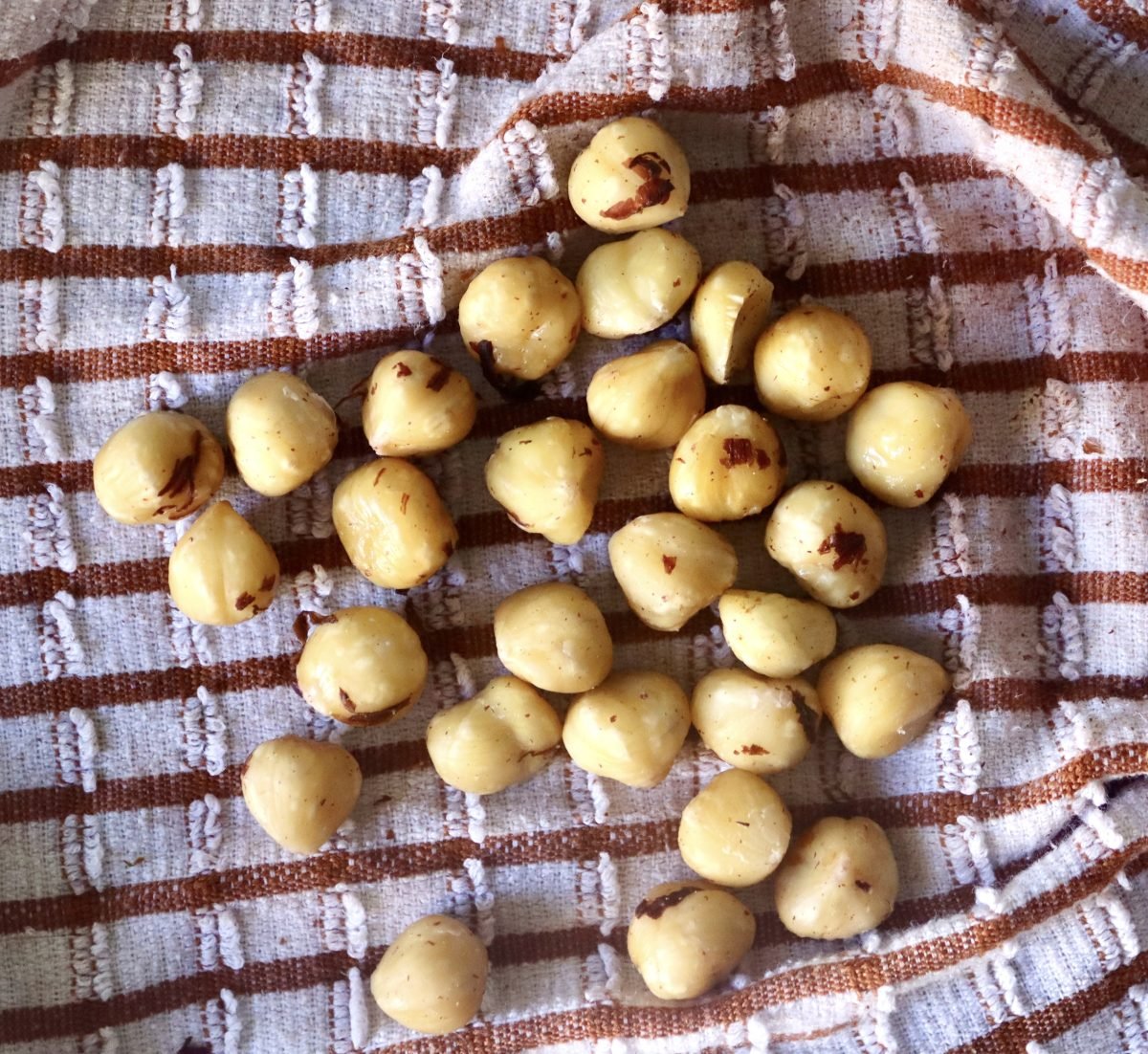Blanched and skinned hazelnuts in a white and brown checked kitchen towel.