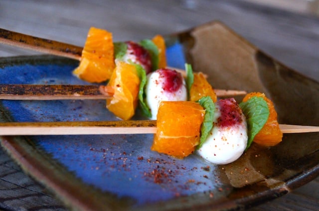 Citrus Caprese Kebabs on a ceramic blue and beige, square dish