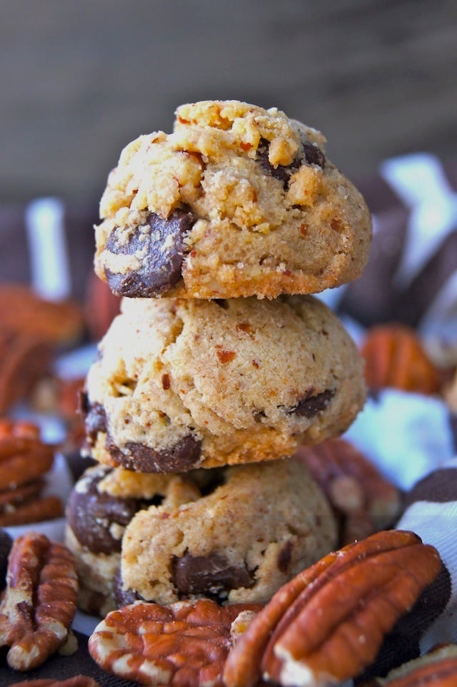 Pecan Praline Chocolate Chip Cookies in a stack surrounded with pecans.