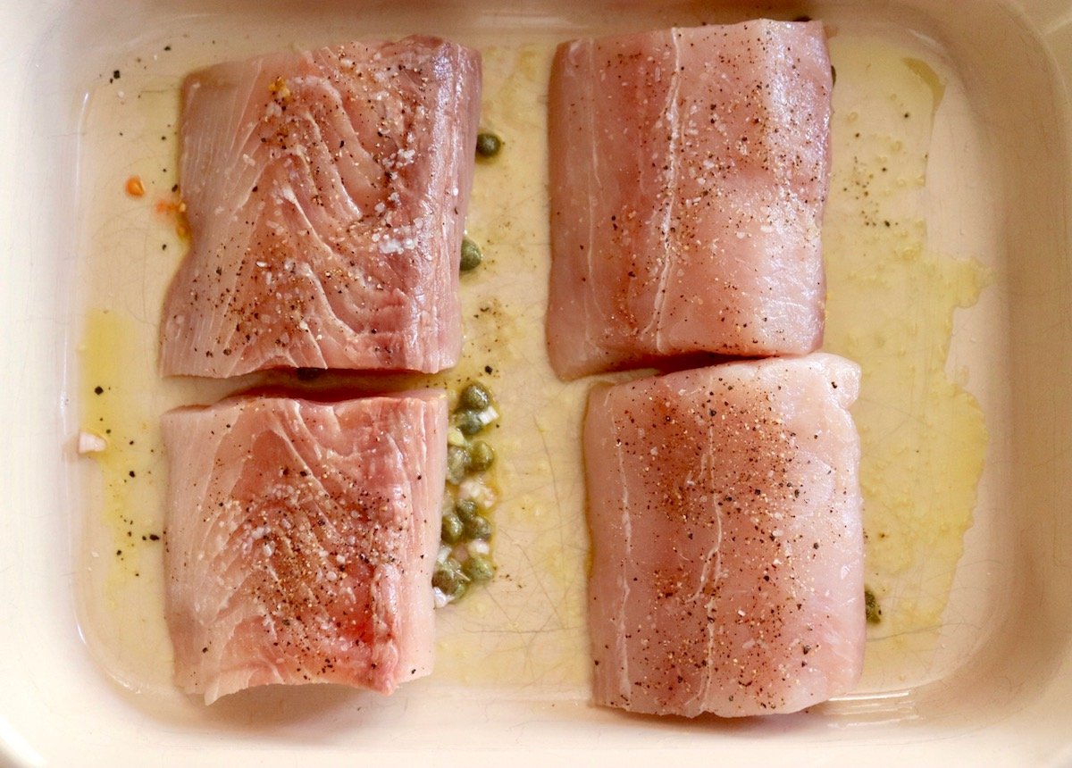 4 Mahi Mahi fillets in a baking pan with oil and capers.