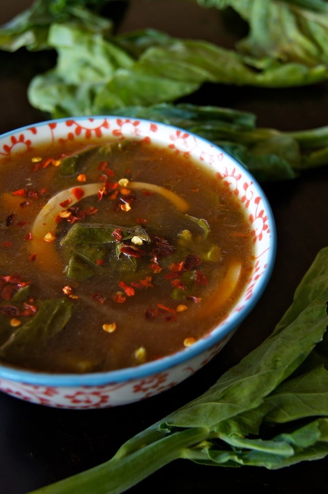 Miso Gai Lan Egg Soup Recipe in a white and red floral, ceramic bowl with a light blue rim, surrounded with fresh gai lan.