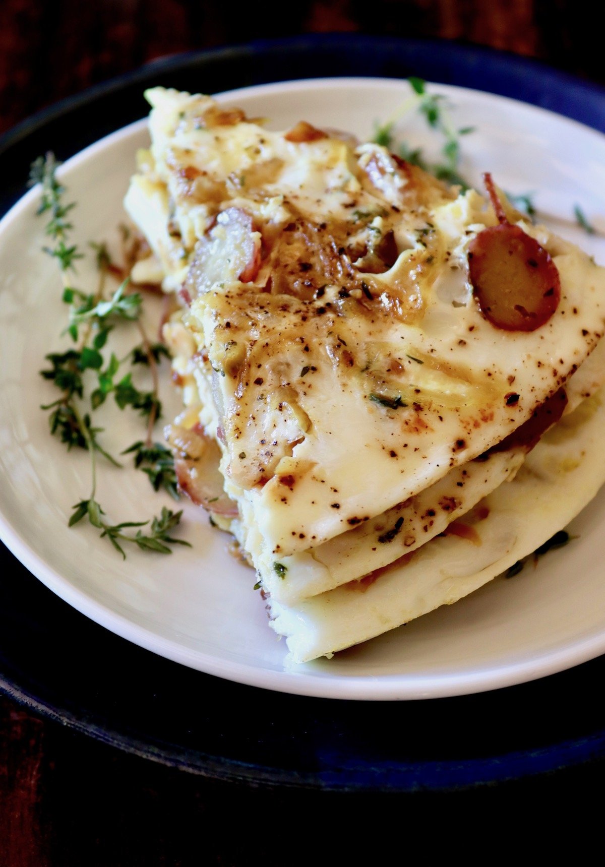 Stack of three slices of egg white potato frittata on white plate.