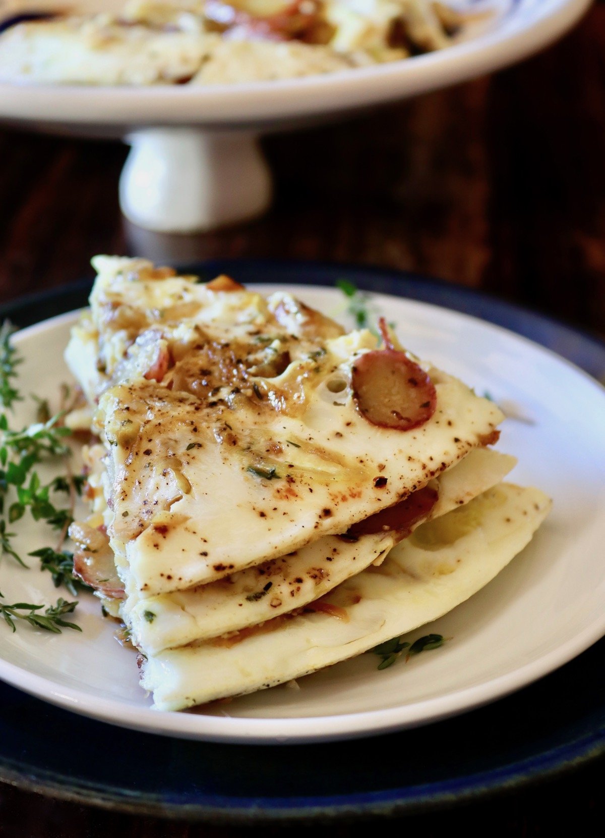 Stack of three slices of egg white potato frittata on white plate with platter behind it.