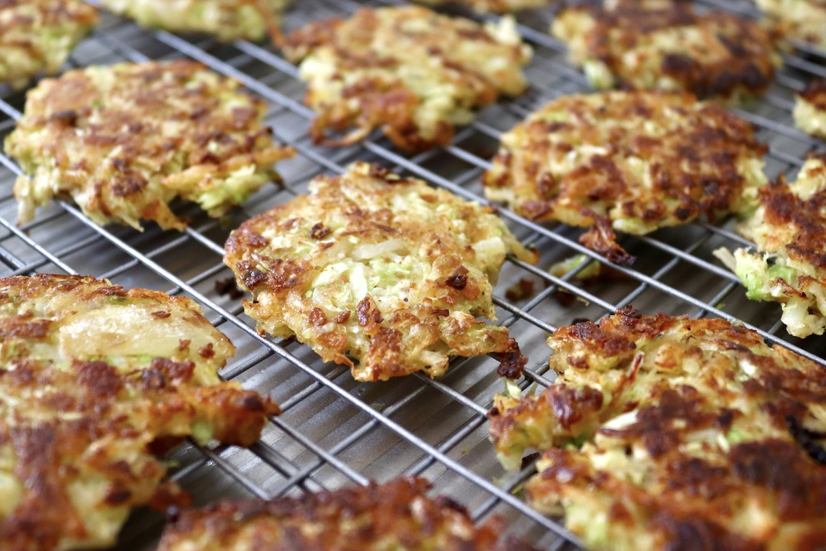 Cabbage-Potato-Pancakes Several crisped, golden-brown cabbage potato pancakes on a wire cooling rack.