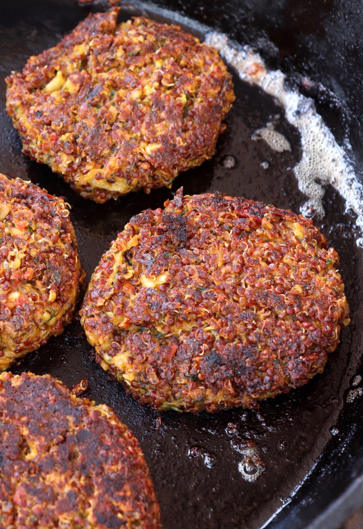 cooked red quinoa burgers on cast iron skillet