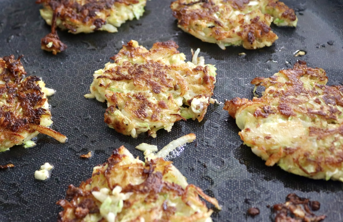 Cabbage-Potato-Pancakes Several golden brown cabbage potato pancakes in skillet.