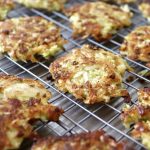 Several crisped, golden-brown cabbage potato pancakes on a wire cooling rack.