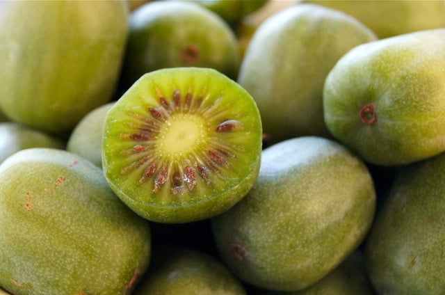 a pile of Baby Kiwi fruit with one sliced in half.