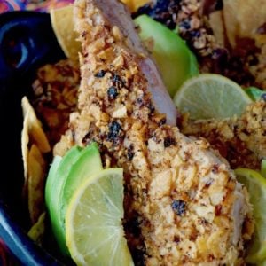 One tortilla-crusted pork chop with lime and avocado slices