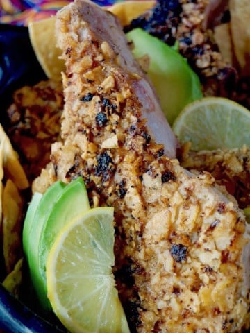 One tortilla-crusted pork chop with lime and avocado slices