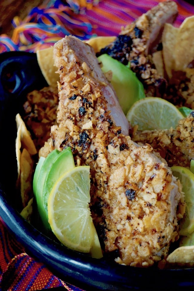 Tortilla Chip Crusted Prok Chops with avocado and lime slices.