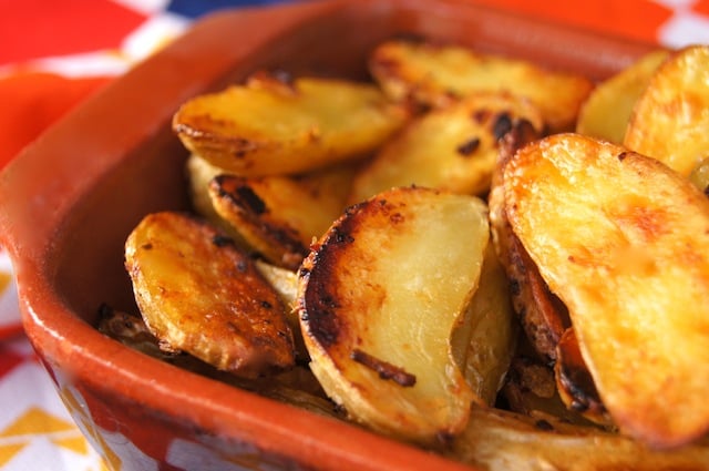 Close up of halved Crispy Onion Fingerling Potatoes in a terra cotta dish.