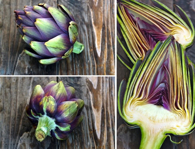 Purple artichokes sliced in half on wood surface.