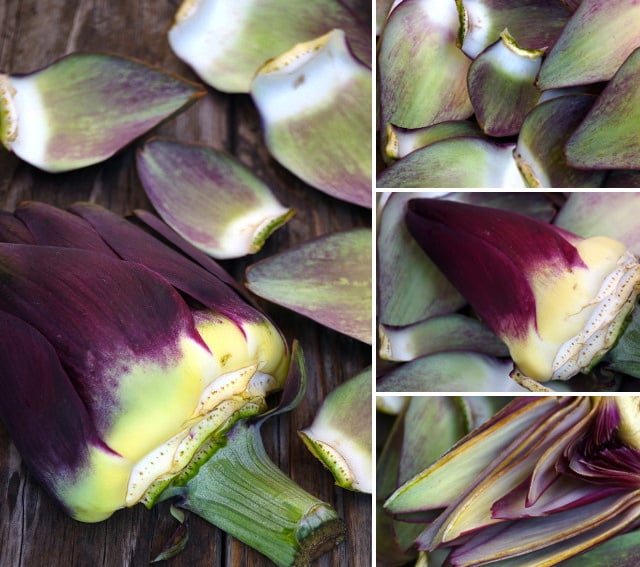 Purple artichoke with many of the leaves peeled off and surround it on wood surface. 