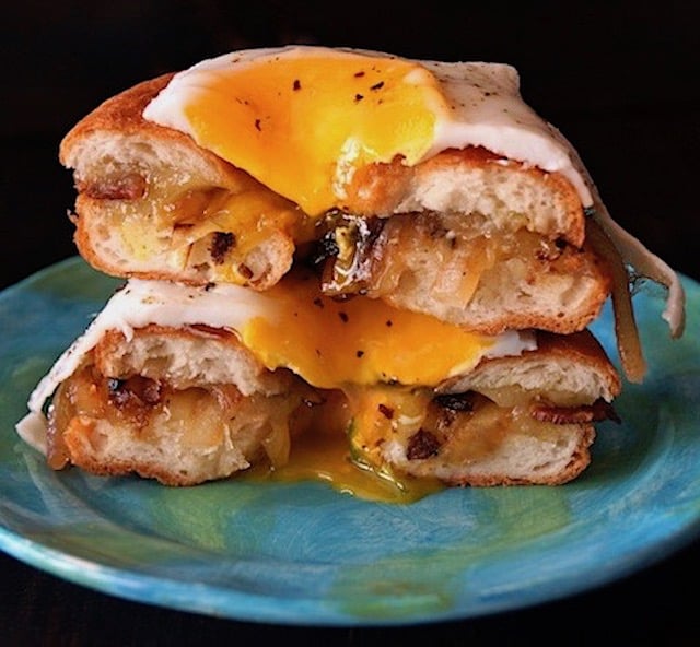 One Breakfast Grilled Cheese Bagel Cut in haf with egg dripping down it.