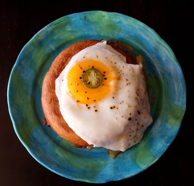 Top view of a Breakfast Grilled Cheese bagel with an Egg on top on a blue-green plate