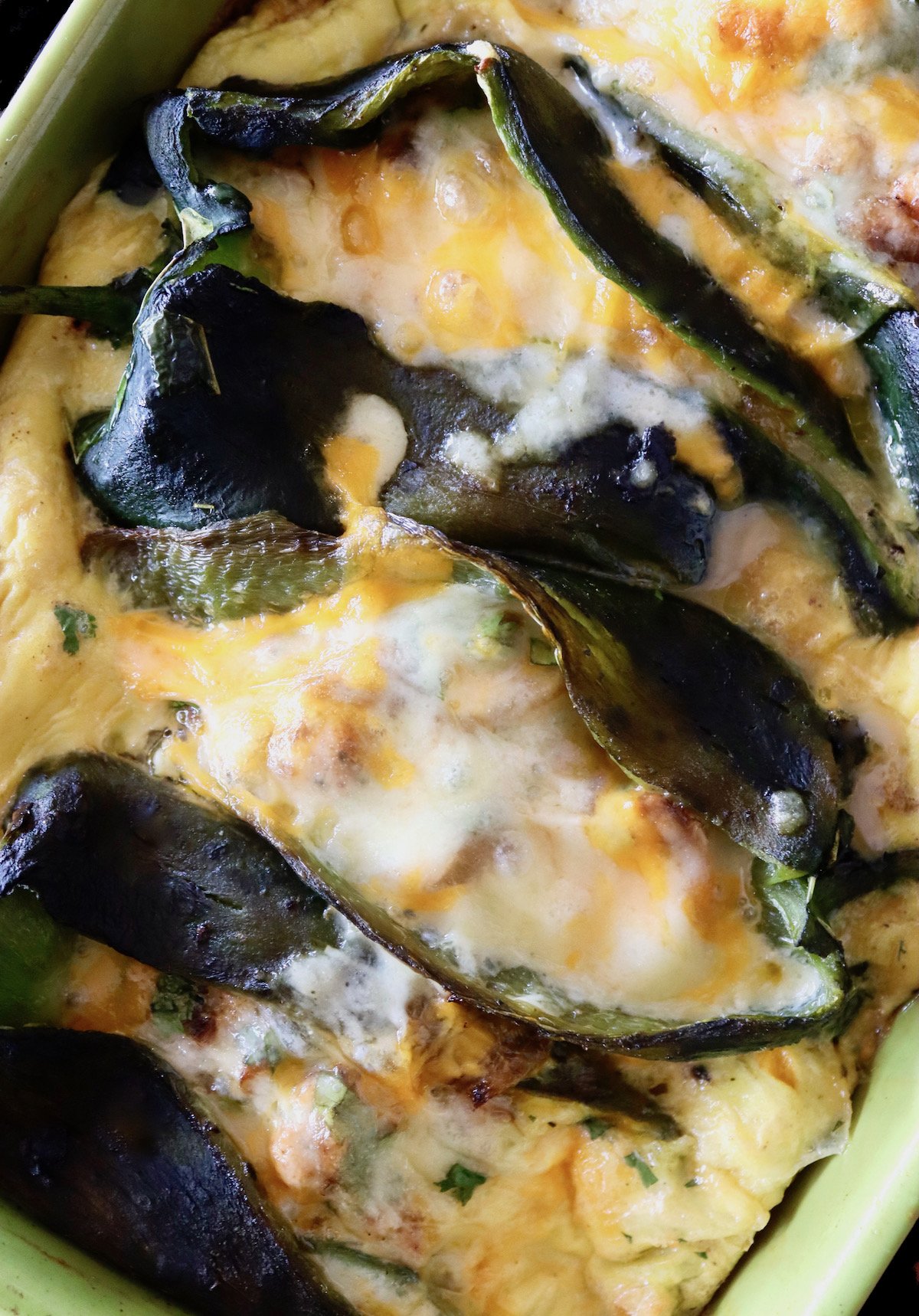 Sausage Cheese and Egg Stuffed Poblano Peppers in a green baking dish.