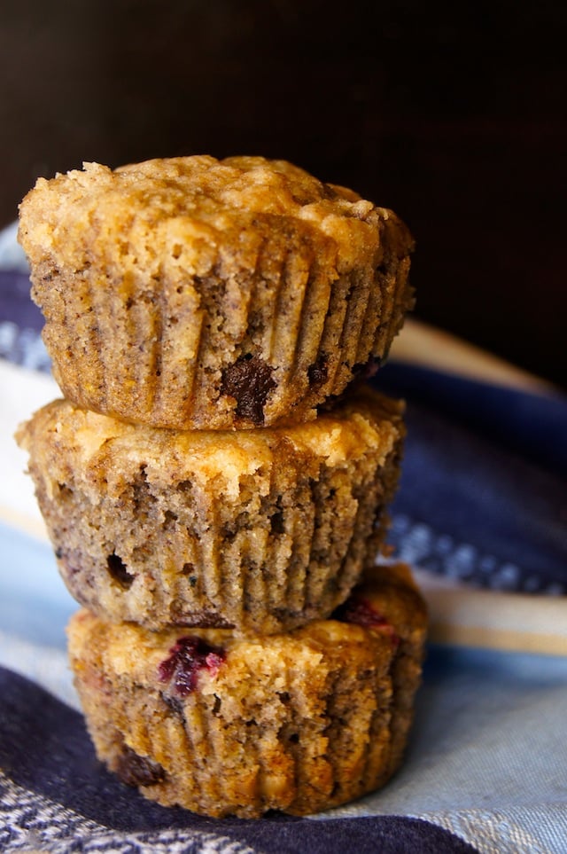 Stack of 3 gluten-free Blue Corn Blueberry Chocolate Muffins on a striped blue cloth napkin.
