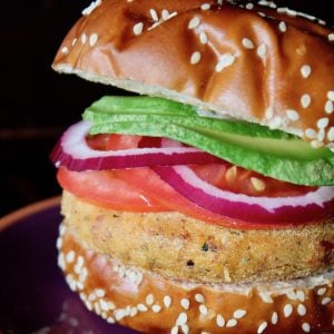 yellow split pea burger in pretzel bun with tomato and avocado