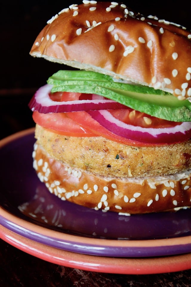 yellow split pea burger in pretzel bun with tomato and avocado