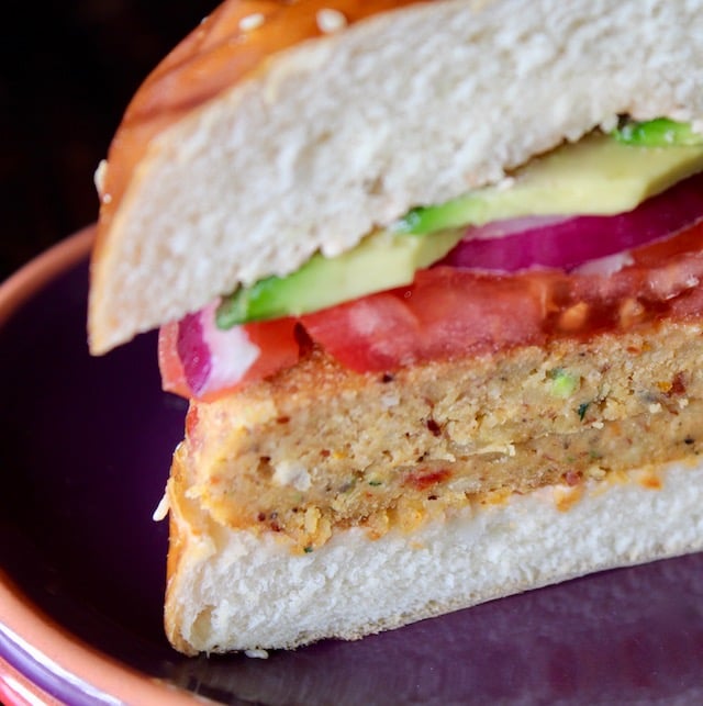 veggie burger in pretzel bun with tomato and avocado, cut in half