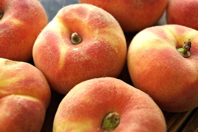 Several dark orange Saturn Donut Peaches next to each other.