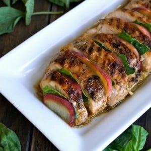 sliced, grilled chicken with peaches and basil on white plate